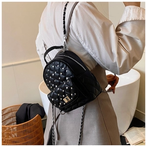 Close-up of black quilted mini backpack with rhinestone studs and silver chain straps