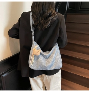 Detailansicht der blauen floralen Denim-Schultertasche mit braunem Teddybär-Anhänger