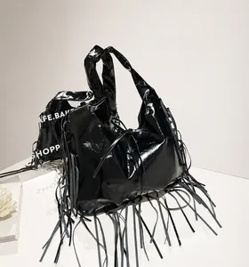 Close-up of black patent leather tote bag featuring long fringes and knotted handle detail