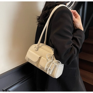 Detail of off-white lychee grain leather bag featuring pearl bow and heart charm