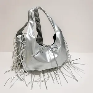 Detail of silver metallic tote bag featuring fringe accents and a small bow detail