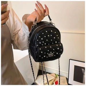 Detailed macro of black quilted leather with rhinestone studs and silver chain strap
