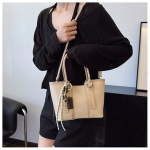Détail du sac à main beige texture tressée avec pendentif chocolat sur tenue noire