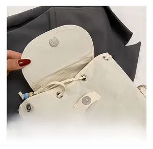 Detailed close-up showing the magnetic metal buckle and drawstring of the white nylon backpack
