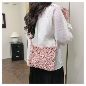 Detail of pink hand-woven bohemian crossbody bag with intricate diamond texture and long tassels