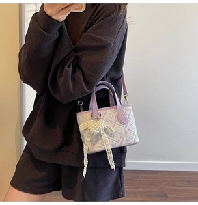 Detail of lavender geometric patterned bucket bag with white pearl bow charm