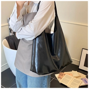 Macro shot of large black glossy tote bag showing premium PU texture and minimalist design