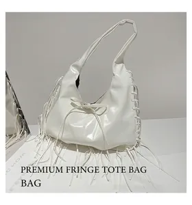 Close-up of white glossy tote bag with long fringe tassels and bow detail