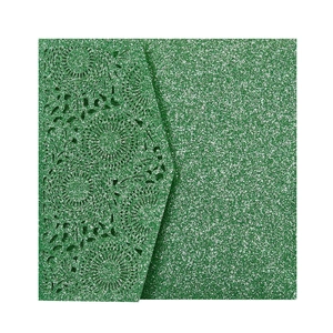 Gros plan d'une carte d'invitation verte pailletée avec motif floral découpé au laser