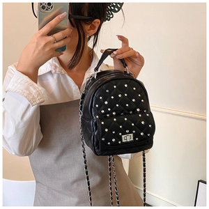 Detail of a black quilted mini backpack with silver rhinestones and chain straps
