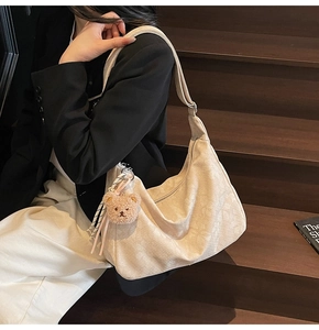 Detailansicht der cremeweißen Schultertasche mit Textur und Bären-Anhänger