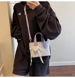 Detail of a purple bucket bag featuring a large pearl bow charm and patterned print