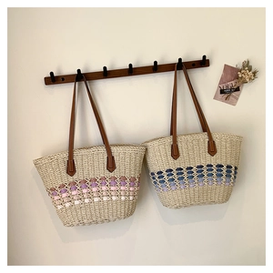 Gros plan de sacs cabas en paille tissée avec détails dégradés sur un support en bois