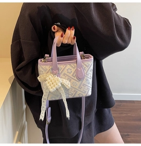 Close-up of lilac jacquard pattern bag with pearl heart pendant and lace bow detail
