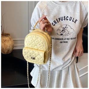 Detail of light yellow quilted mini backpack with rhinestones and gold chain strap