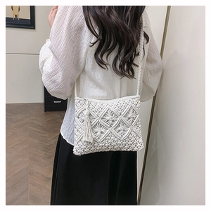 Détail d'un sac bandoulière bohème tissé avec motifs géométriques et pompons décoratifs
