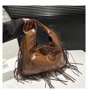 Detailed macro shot of brown PU leather hobo bag with fringe tassels and bow knot