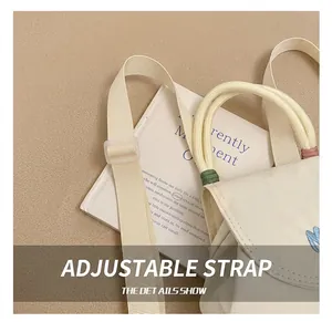 Detail des verstellbaren Riemens und der weißen Canvas-Minibag mit M-Stickerei