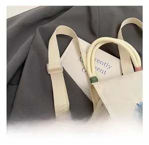 Detail of adjustable strap and white canvas mini bag with blue M embroidery