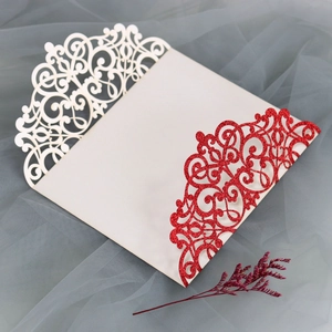 Close-up of laser-cut floral pattern on ivory wedding invitation with red glitter backing