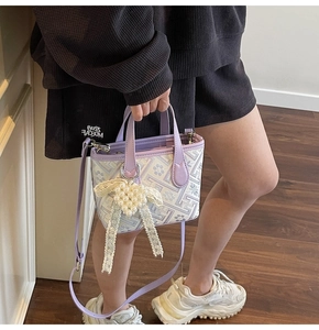 Detail of lavender geometric jacquard handbag with pearl heart charm and leather strap
