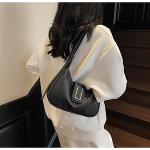 Close-up of black lychee grain leather underarm bag with silver buckle on model