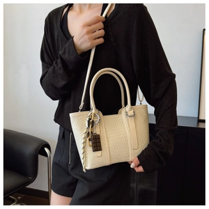 Détail du sac cabas crème avec texture tissée, bandoulière et pendentif chocolat