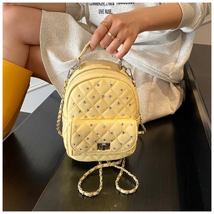 Detail of yellow quilted mini backpack with sparkling rhinestones and silver chain strap