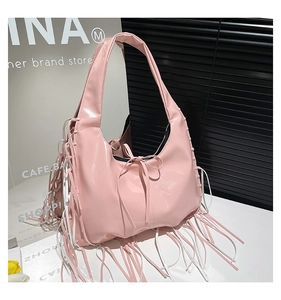 Detailed side view of pink patent leather hobo bag with tassel and bow accents