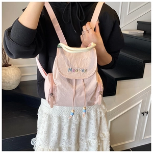 Detail eines rosa Nylon-Rucksacks mit bunten Stickereien und Perlen-Kordelzug-Anhänger