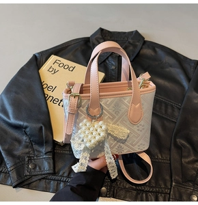 Close-up of pink and beige mini tote bag with pearl heart pendant and lace bow detail