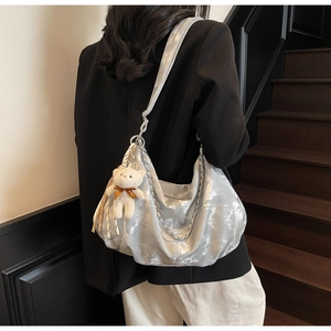 Detail of silver metallic hobo bag with pleated texture and plush bear pendant