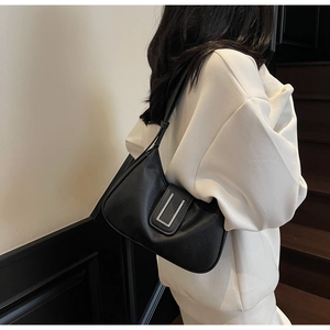 Close-up of a black lychee texture hobo bag with silver metal buckle on a model shoulder
