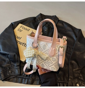 Detail of floral bucket bag with pearl bow charm and pink leather strap on artistic books