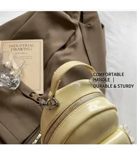 Detailed shot of yellow PU backpack handle with silver D-rings and metal zipper closure