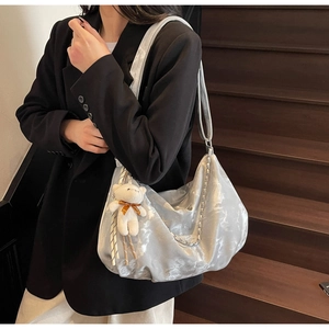 Detail of silver metallic hobo bag with metal chain strap and white plush bear charm
