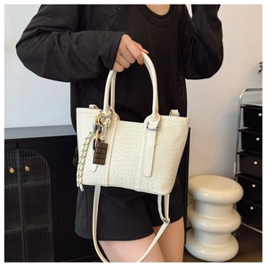 Détail du sac à bandoulière blanc crème avec breloque chocolat décorative et sangle