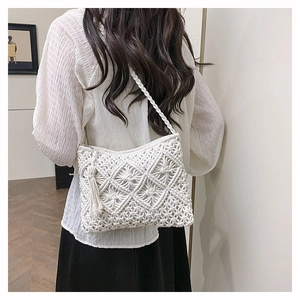 Detail of white macrame shoulder bag with diamond weave pattern and bohemian tassels