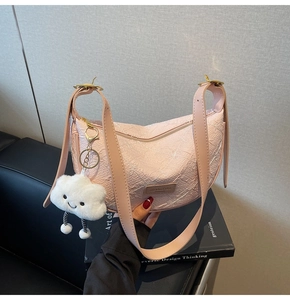 Close-up of pink dumpling bag with embossed texture and a cute plush cloud charm