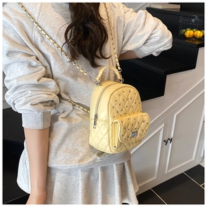 Detail of light yellow quilted mini backpack with sparkling silver rhinestones and chain strap