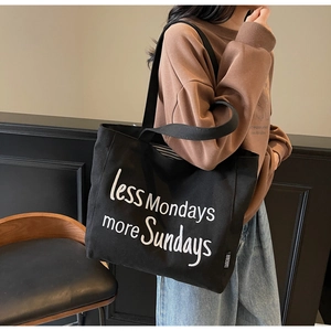 Detail view of black canvas tote bag with white less Mondays more Sundays embroidery