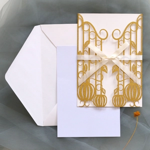 Detail of laser-cut pumpkin invitation with gold glitter and white silk ribbon bow