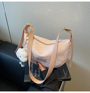 Close-up of pink crescent dumpling bag with pleated texture and white fluffy cloud charm