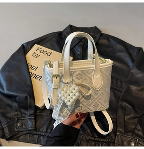 Detail of white embroidered tote bag with pearl heart charm and lace on leather jacket