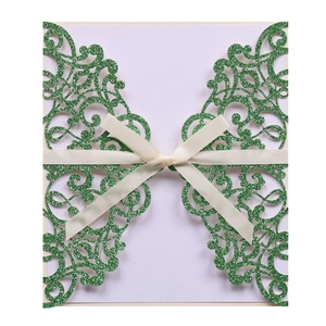 Forest green laser-cut wedding invitation cover with gold glitter finish and cream ribbon
