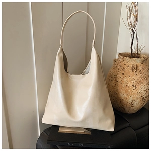 Minimalist cream faux leather hobo bag displayed on an elegant stand with a soft studio look