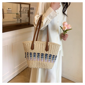 Détail du sac cabas en paille avec corps beige, motifs colorés et anses en cuir marron
