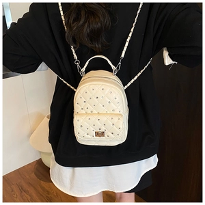 Detail view of cream quilted mini backpack with rhinestone studs and chain straps