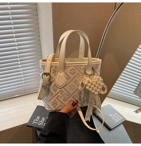 Detail showing white patterned crossbody bag with pearl heart charm and strap