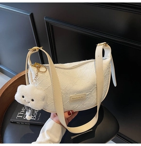 Detailed shot of white dumpling bag with pleated texture and cloud plush charm detail